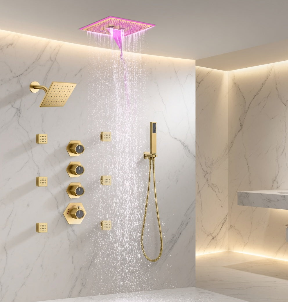 A modern wall-mounted shower system with a square rain shower head dispensing water, a handheld shower wand, multiple control valves, and warm ambient lighting in a marble-look bathroom wall.